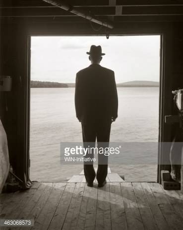 463068573-man-standing-in-a-boat-shed-looking-out-to-gettyimages.jpg